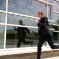 A Stock Photograph of a Young Adult Businessman Outside a Modern Office Block Running
