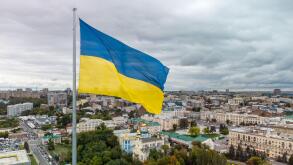 Flag of Ukraine waving with epic gray cloudscape, autumn city aerial view near river Lopan embankment, Svyato-Pokrovskyy Monastyr in Kharkiv, Ukraine