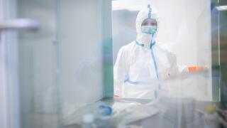 Lab technician wearing cleanroom overall at material sluice