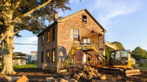 Plymouth, Massachusetts, USA - Excavation equipment lines up next to an old house in Massachusetts as contractors prepare for demolition.