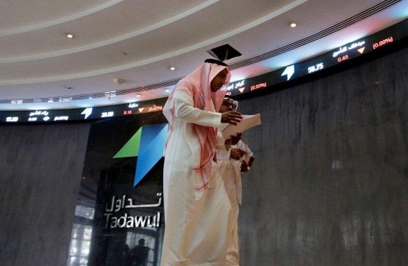 Saudi men walk at the Tadawul Saudi Stock Exchange, in Riyadh, Saudi Arabia, Monday, June 15, 2015. Saudi Arabia's stock market, valued at $585 billion, opened up to direct foreign investment for the first time Monday, as the kingdom seeks an economic boo