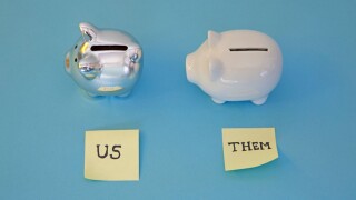 two piggy banks with post it notes of "us" and "them" .