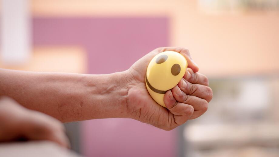 Hands squeezing or pressing stress ball at home to release stress - concept of stress buster