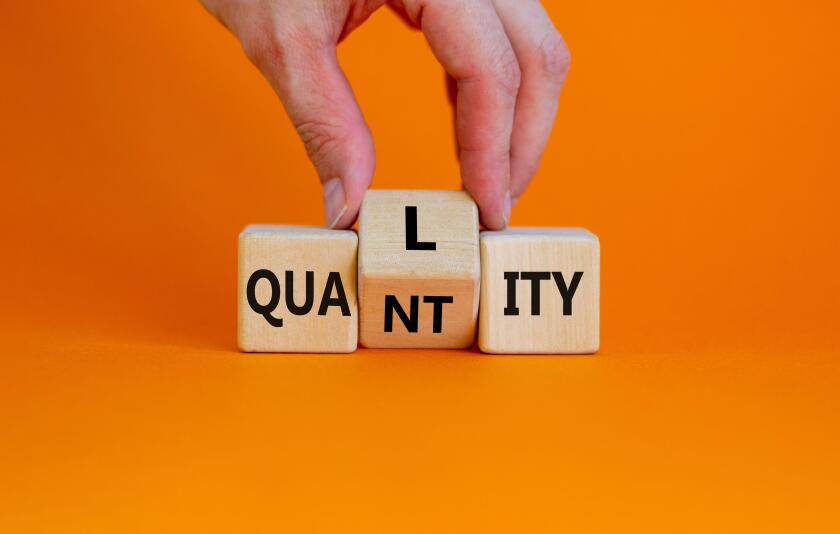Quality over quantity symbol. Businessman turns cubes and changes the word 'quantity' to 'quality'. Beautiful orange table, orange background, copy sp