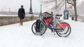 London, UK; 28th February 2018; Man walks past Line of Santander Bikes During Snowstorm