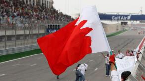A marshal celebrates waving Bahrain flag after the Bahrain Formula One Grand Prix at the Formula One Bahrain International Circuit in Sakhir, Bahrain, Sunday, April 22, 2012. (AP Photo/Luca Bruno)