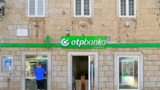 A tourist using an ATM outside an Otp Banka in Korcula Town, Korcula Island, Croatia, Dalmatia, Dalmatian Coast, Europe.