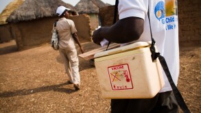 A community health nurse and a volunteer visit homes to vaccinate children against polio in the village of Gbulahabila, Ghana