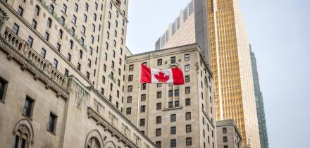 Canadian flag in front of a business building and an older skyscraper in Toronto, Ontario, Canada
Old and new buildings seen from the ground with a c