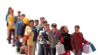 Miniature figure people forming an orderly queue against a white background
