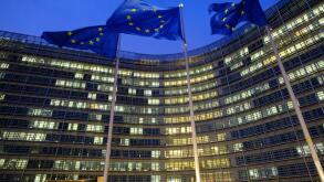 Belgium, Brussels: European Union Flags in front of the Berlaymont building, headquarters of the European Commission, in the evening