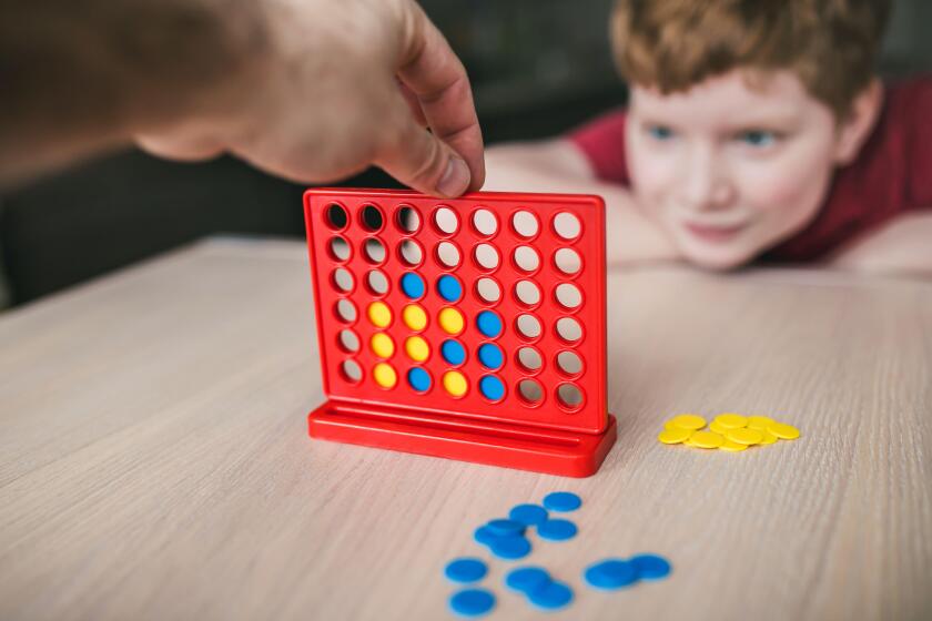 Father and son playing a board game of "collect four in a line" - family leisure