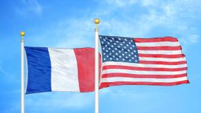 France and United States two flags on flagpoles and blue cloudy sky