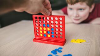 Father and son playing a board game of "collect four in a line" - family leisure