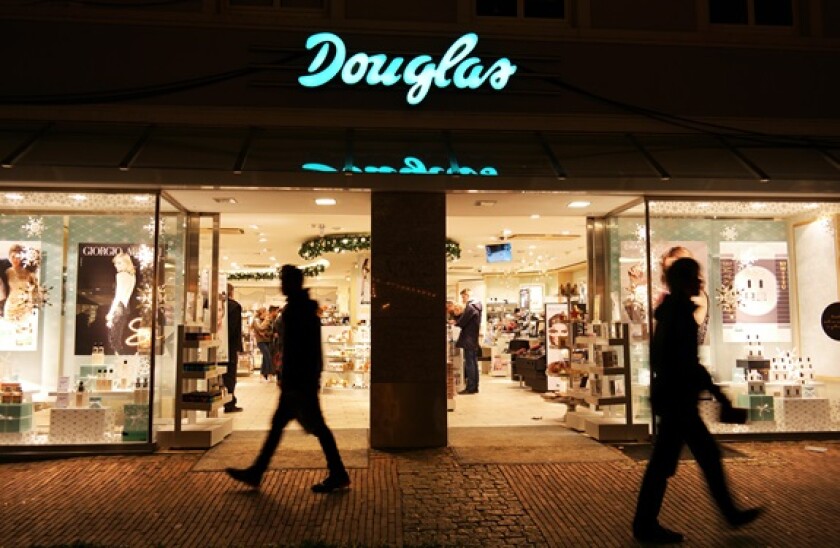 Silhouette of man as he passes a Douglas store by night.