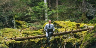 Business man works remotely in lush forest in the morning
