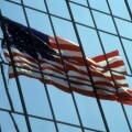 American flag reflected in a glass office building