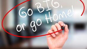 Man Hand writing Go Big or Go Home with black marker on visual screen. Isolated on office. Business, technology, internet concept. Stock Image