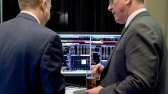Investors talking in front of computer screen showing stock market trends - USA