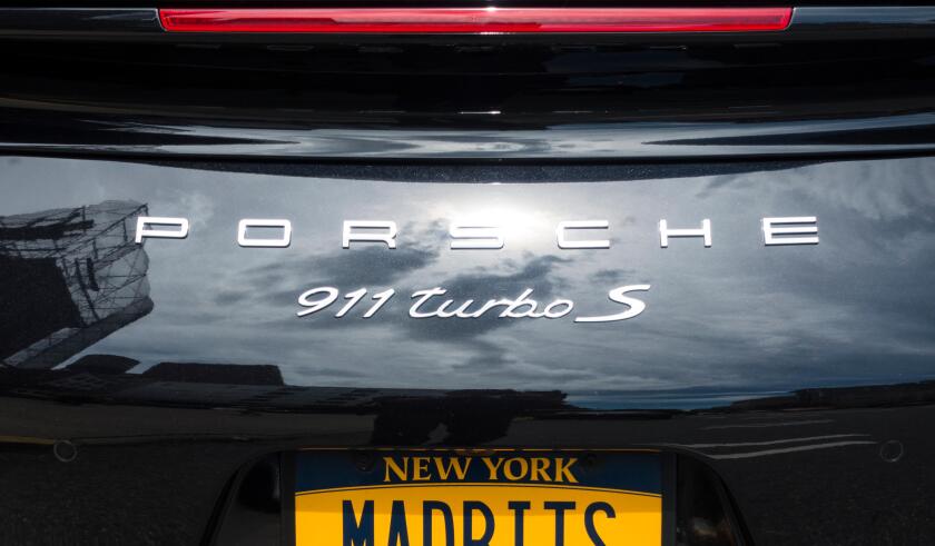 The back end of a black Porsche 911 Turbo S with a New York license plate