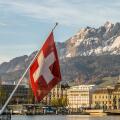 Swiss National Flag in Lucerne in Central Switzerland with the mountain range of Mt Pilatus in the background