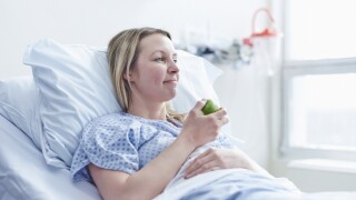 Patient lying in hospital bed eating apple