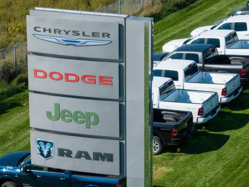 A sign with the Chrysler, Dodge, Jeep and RAM logos on into, out from a large car dealership selling the popular Stellantis brands.