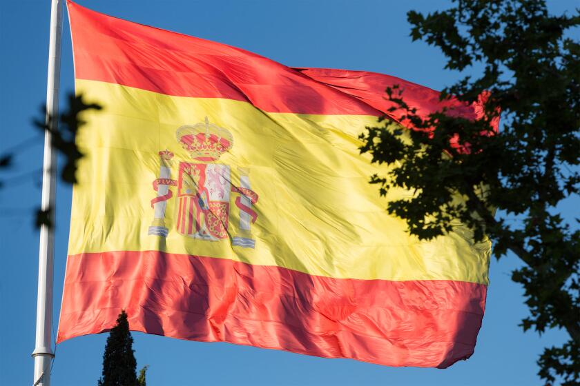 Huge Spanish flag blowing in the breeze in a square in Madrid, Spain