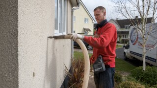 Man filling cavity wall with insulation, Devon