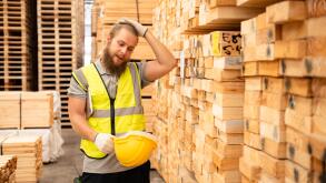Portrait of a male worker with helmet and safety vest in wooden warehouse