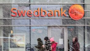 People walk past a Swedbank branch in Riga February 14, 2012. Swedish banking group Swedbank said on Tuesday it would slash costs in 2012 to maintain profitability in the face of tough new capital rules and the risk of recession in Europe. Swedbank, the b