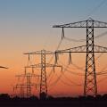 Silhouettes of a wind turbine and electric power posts during sunset