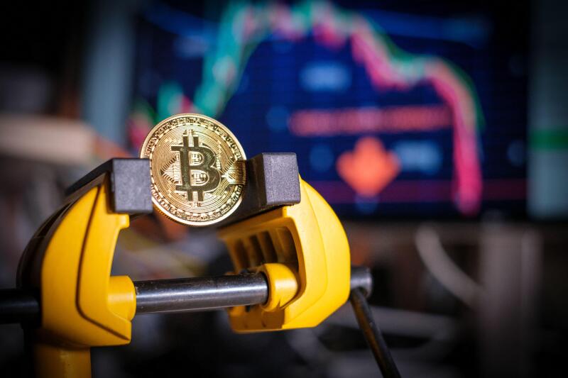 a bitcoin coin is clamped in a vice