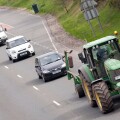 Queue of traffic behind a slow moving vehicle farming tractor on the A75 road UK