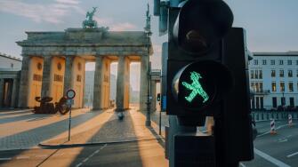 Ampelmann Berlin green traffic light close-up with Brandenburg gate at background at sunrise
