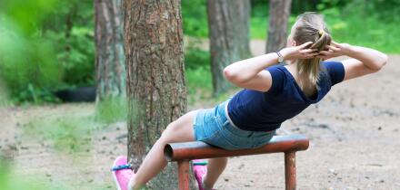Woman doing abs workout in the forest.