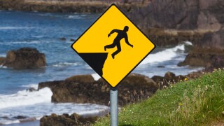 A yellow warning sign depicting a person falling off a cliff;County kerry ireland