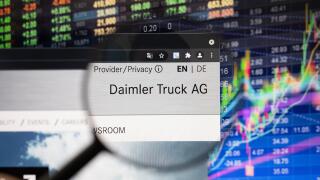 Daimler Truck AG company logo on a website with blurry stock market developments in the background, seen on a computer screen