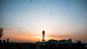 montjuic cableway tower at dawn with sun rising behind tower during sunrise with spectacular rays, a landmark of barcelona with the port and cruise sh