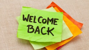 welcome back - handwriting on a green sticky note against canvas board