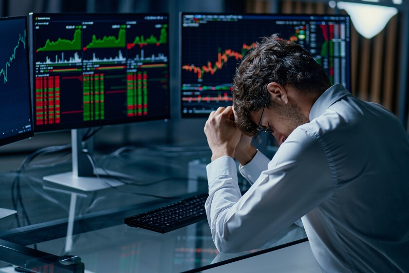worried young investor sitting at a computer desk .