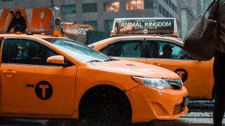 New York: Yellow taxi cab speeds through busy traffic of downtown New York City on a rainy day. East 42nd strret, NY. Cloudy stormy weather