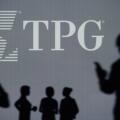The TPG Capital logo is seen on an LED screen in the background while a silhouetted person uses a smartphone (Editorial use only)