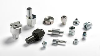 Assorted spare aluminium and iron parts and precision engineered components scattered on a white background with shadows