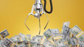 Robotic claw of grab machine is grasping stacks of one hundred US dollar bills. Earning profit, successful investment and business competition