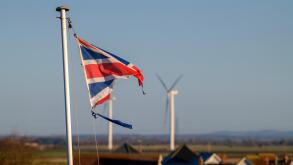 A tattered Union Jack flag fluttering in the wind against a blue sky.