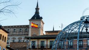 Toledo, Spain - December 23, 2024: A Spanish flag flies atop Alcazar from Zocodover square during christmas time