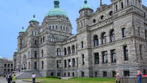 Victoria, BC, Canada -  Visitors walk past the front of the baroque style provincial parliament building of British Columbia, in the ca