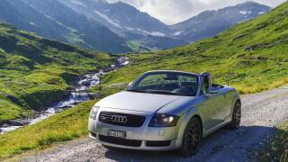 1999 Audi TT quattro roadster mark I (type 8N), silver metallic, roof retracted, on an unpaved Alpine road in Uri, Switzerland.