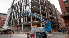 cherry picker elevated platform guiding building panels on construction site Boston USA
